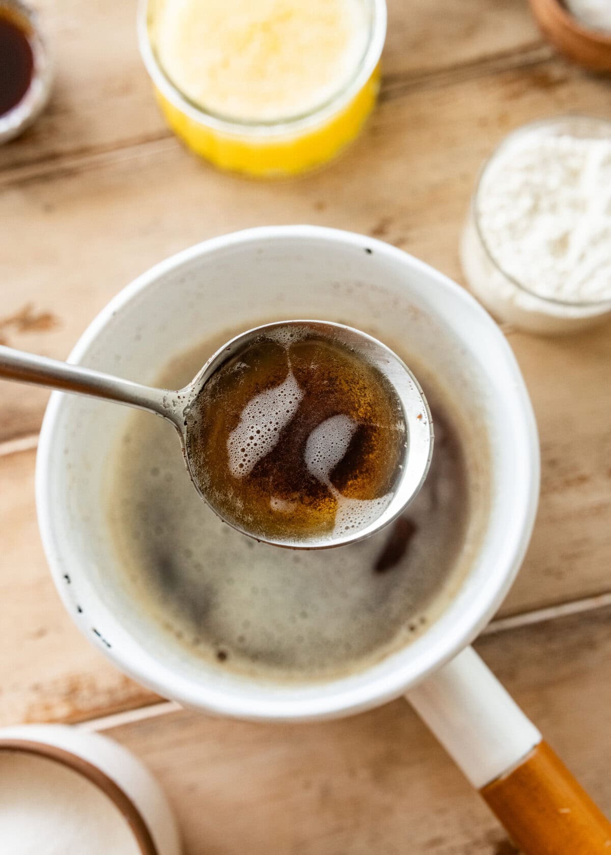 Browned butter in a sauce pan with a spoon holding some up.
