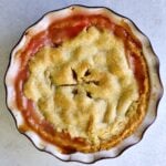 whole rhubarb pie baked and ready to eat. Jammy filling coming out of the flaky buttery crust.