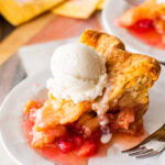 a slice of rhubarb pie on a plate, topped with ice cream with a fork and more pie nearby.