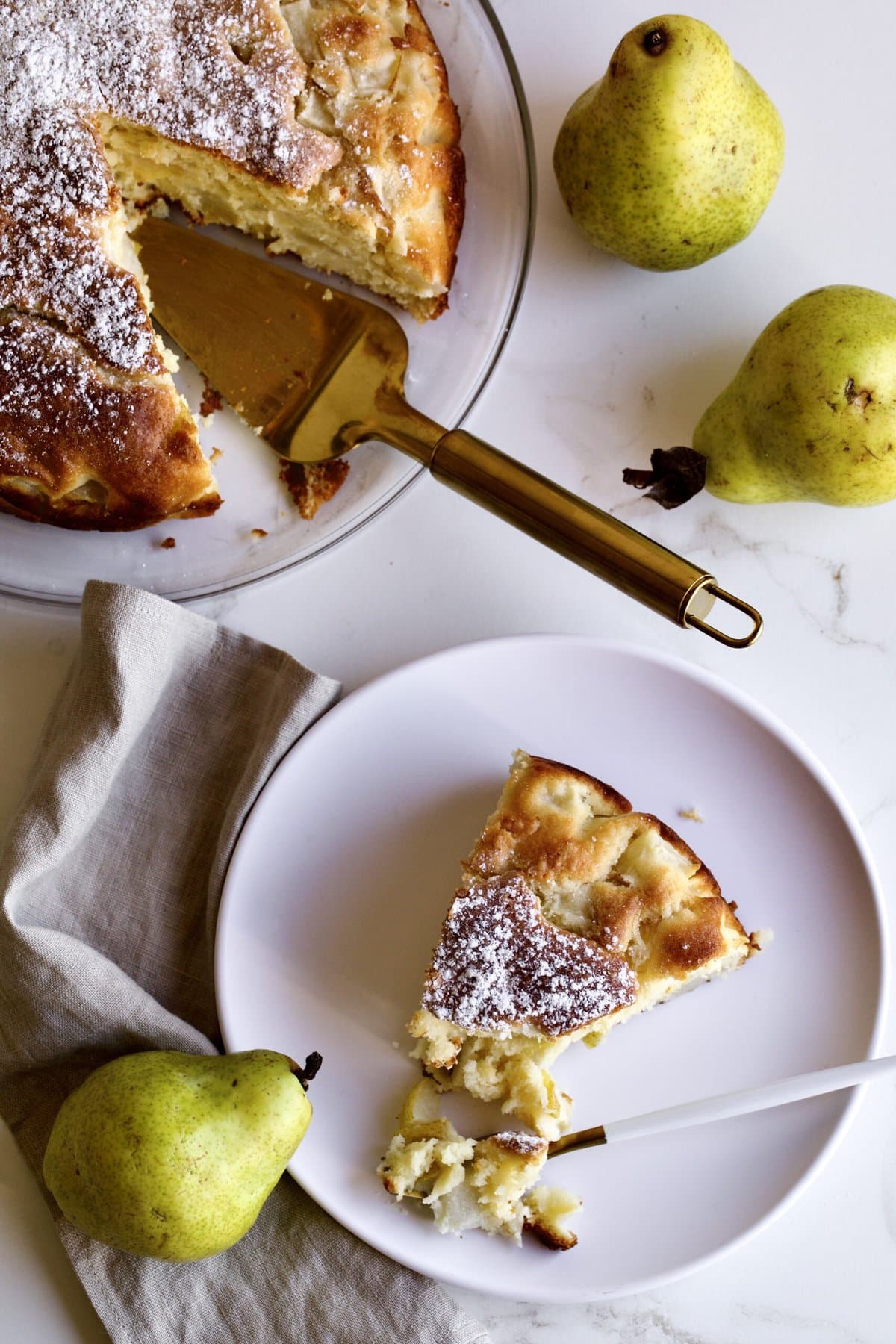 Italian pear cake recipe. Slice of cake on a plate with fresh pears as the background.