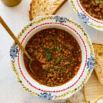 two beautiful antique looking bowls full of the classic italian lentils. A golden spoon on the side.