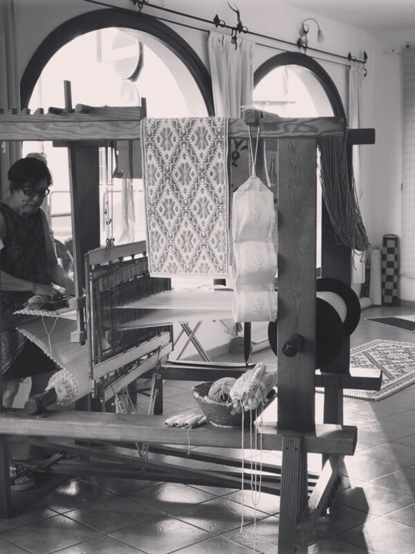 Black and white photo of a woman making a tapestry.