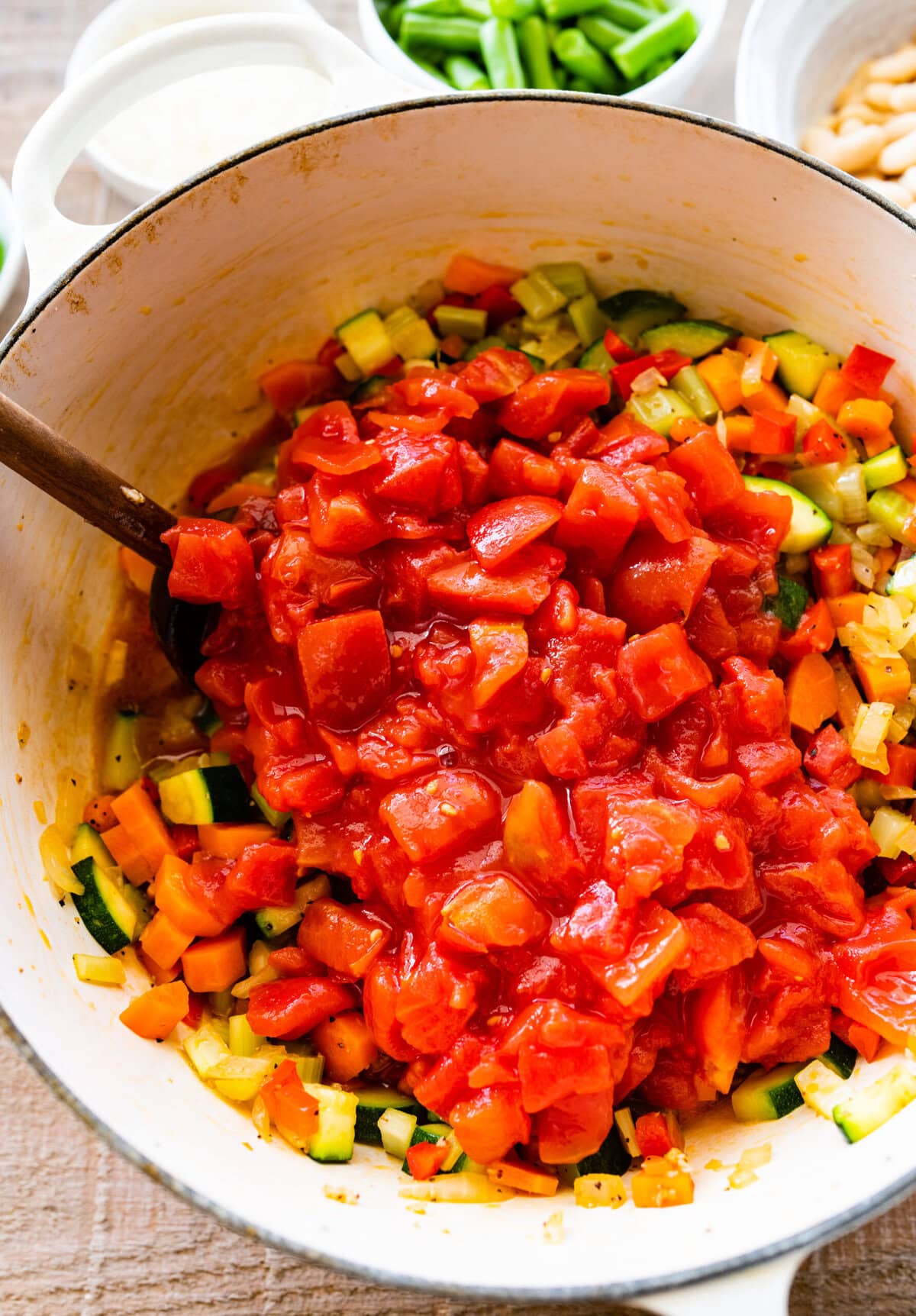 How to make Classic Minestrone Soup Recipe Instructions- add the crushed tomatoes. Stir with wooden spoon.