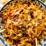finished classic Italian ragu meat sauce to the pan with serving utensils. Served in a decorative Italian pasta serving bowl.