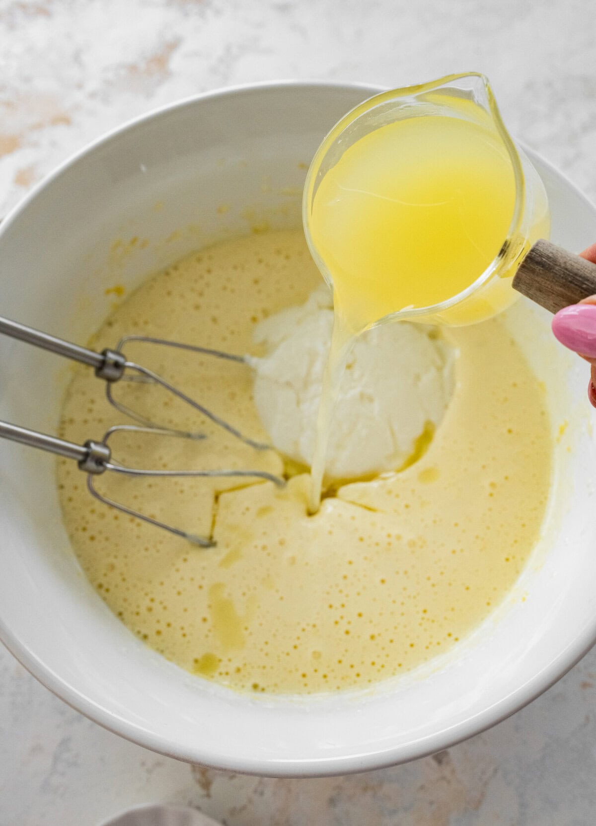 Drizzling lemon juice into the cake batter. 