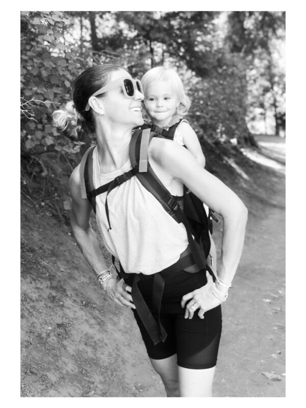 Black and white photo of a woman wearing a child on her back.