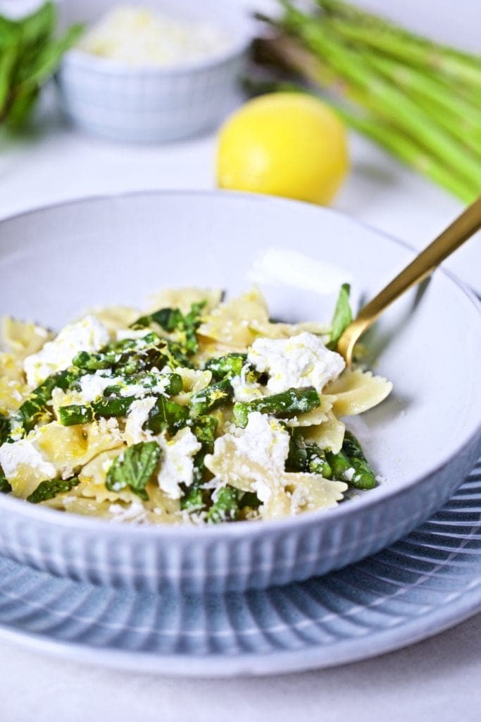 Lemon ricotta pasta with asparagus in a bowl with a fork.