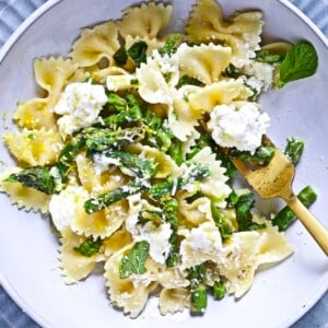 Fork grabbing lemon ricotta pasta with asparagus from a bowl.