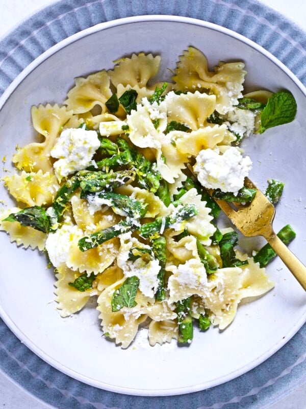 Fork grabbing lemon ricotta pasta with asparagus from a bowl.