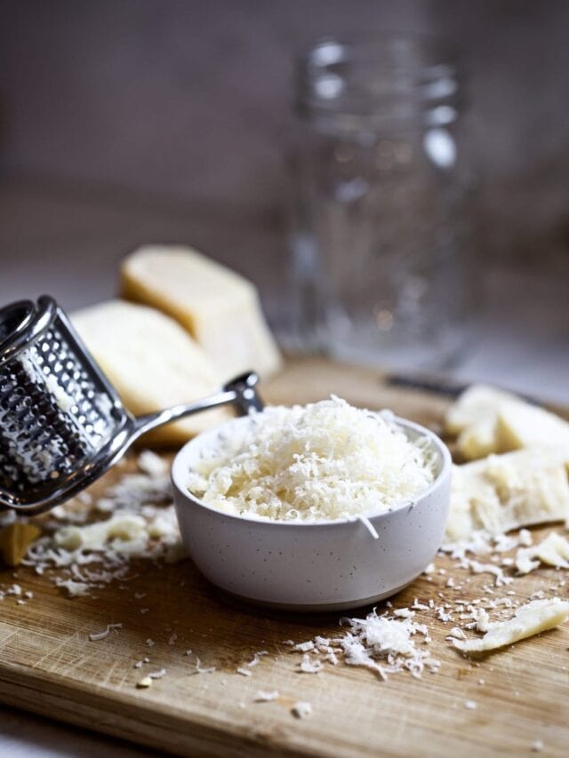 Cheese grater next to a small bowl of grated cheese.