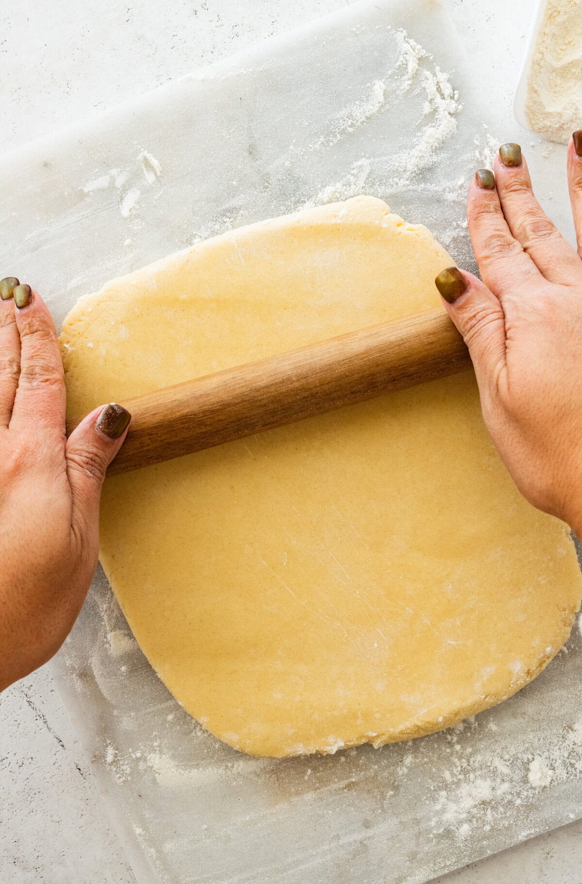 Rolling out the dough to make cutout soft sugar cookies.