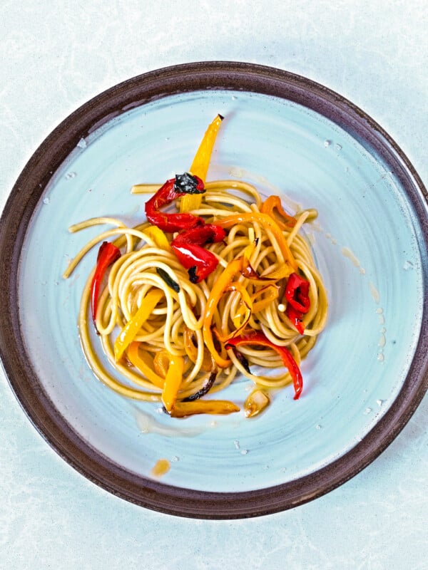 bucatini pasta with roasted peppers in olive oil on a round plate
