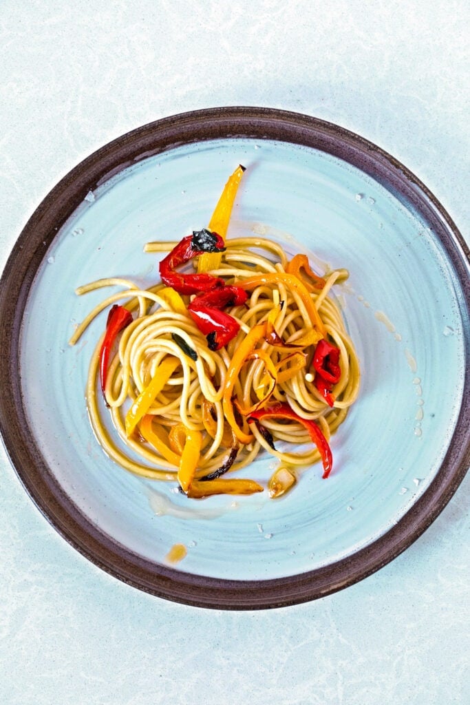 bucatini pasta with roasted peppers in olive oil on a round plate 