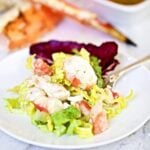 king crab on a plate with lettuce and cup of salad dressing