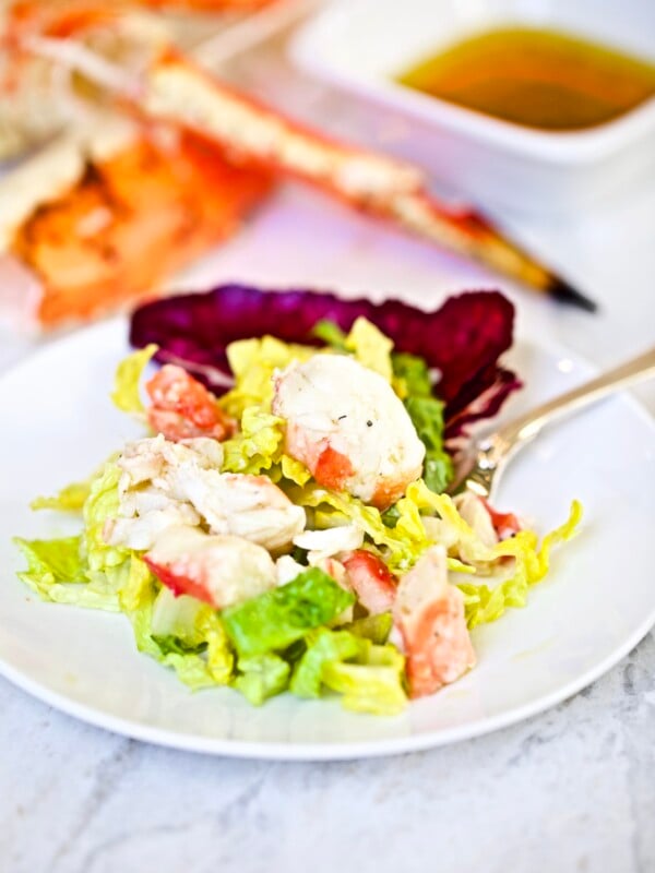 king crab on a plate with lettuce and cup of salad dressing