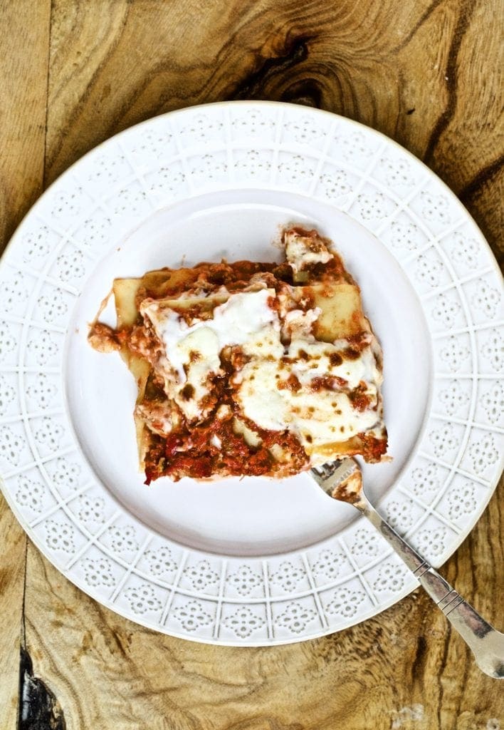 slice of lasagna on a white plate with a fork ready to eat it