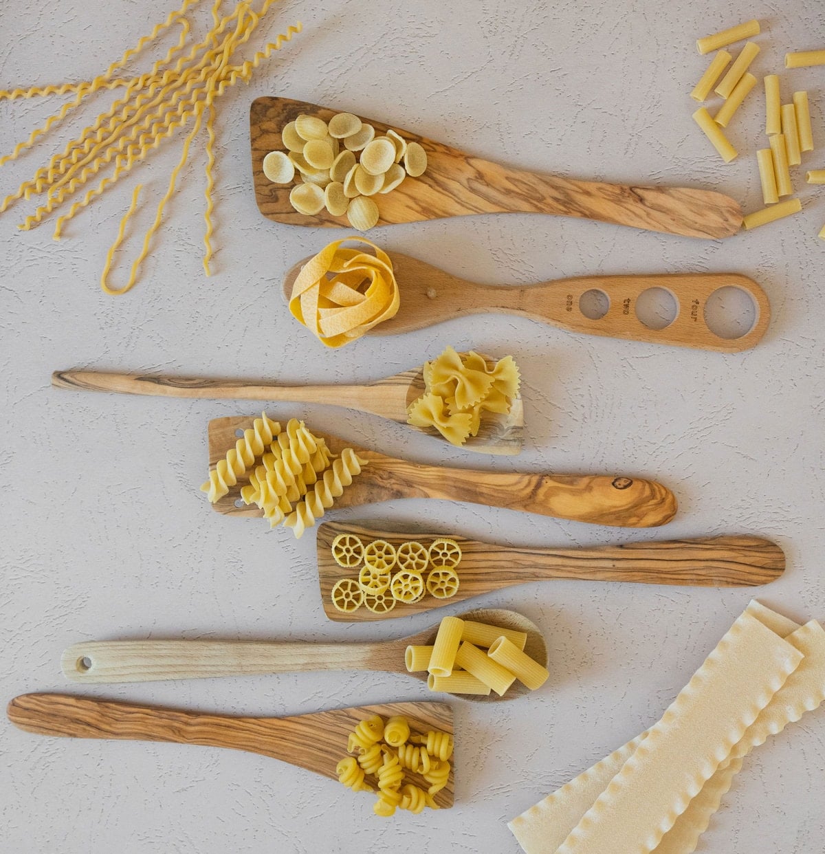 different pasta shapes with wooden spoons
