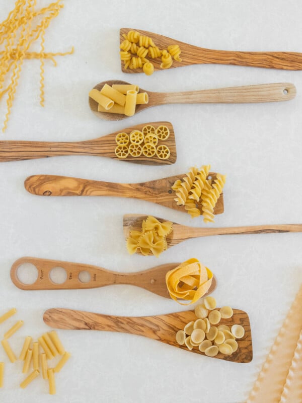 different pasta shapes with wooden spoons