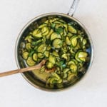 zucchini and onion in a pan with a wooden spoon
