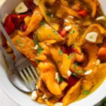 Roasted peppers in a bowl with utensils inside.