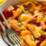 Roasted peppers in a bowl with utensils inside.