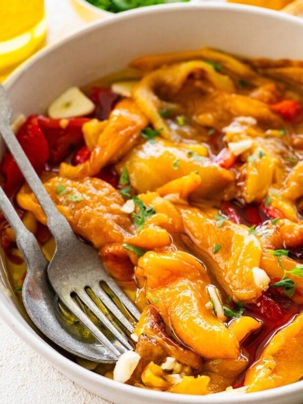 Roasted peppers in a bowl with utensils inside.