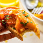 Roasted peppers on a piece of bread with a bite taken out,