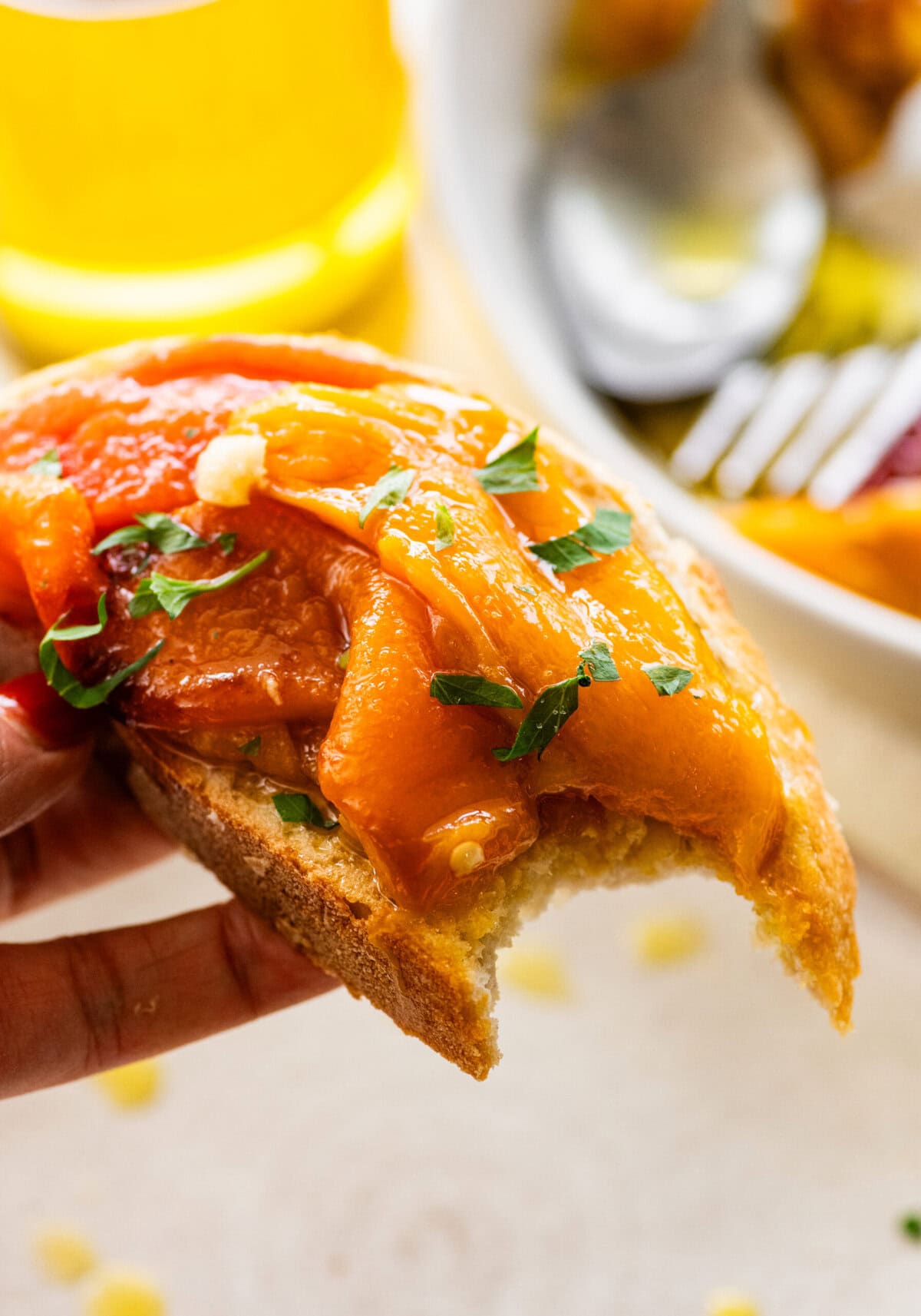 Roasted peppers on a piece of bread with a bite taken out,
