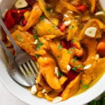 Roasted peppers in a bowl with utensils inside.
