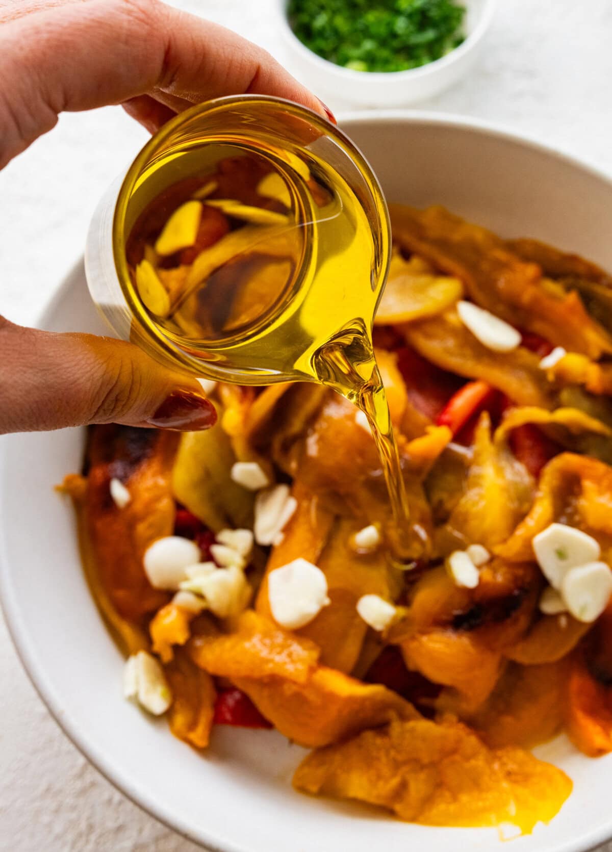 Pouring olive oil on top of the peppers.