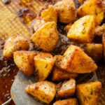 A serving utensil lifting up some potatoes.