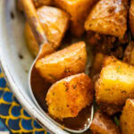 A bowl of potatoes with a spoon resting inside.