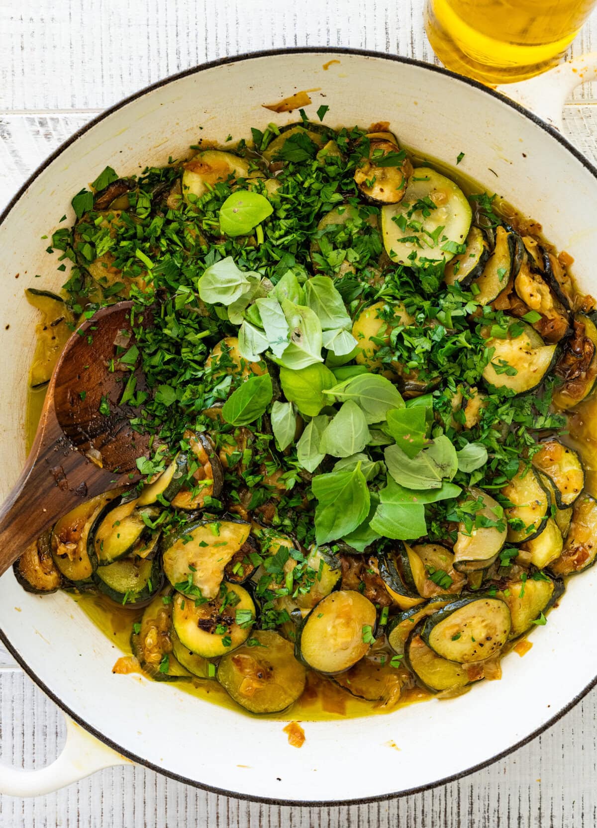 Fresh herbs added on top of the zucchini in the skillet.
