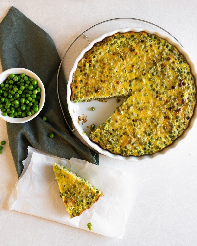 peas frittata served in a round dish with one piece on a plate