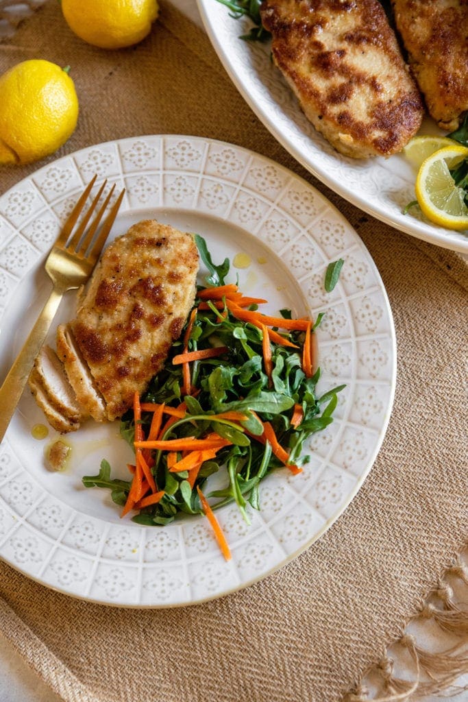 pan fried chicken breast on a plate with salad and carrots