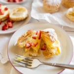 puff pastries filled with cream on a plate with strawberries
