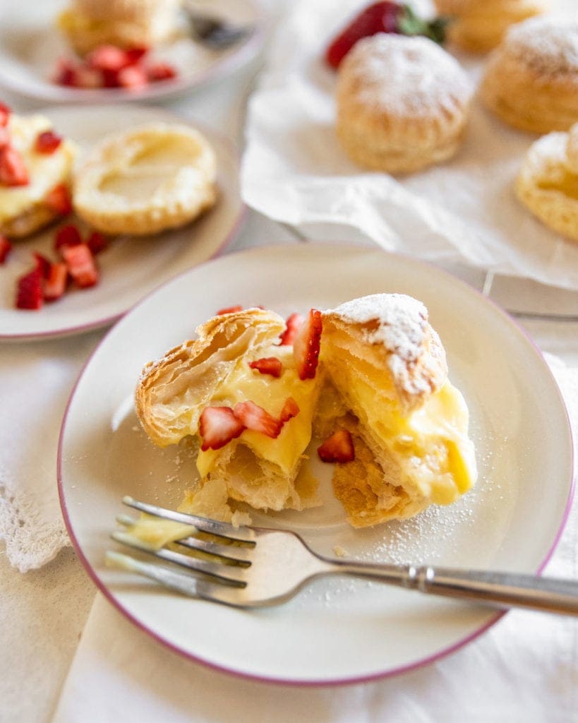 puff pastries filled with cream on a plate with strawberries