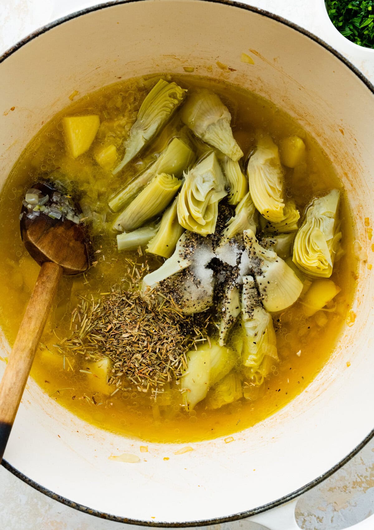 making the artichoke soup- add the spices and herbs to the pot.