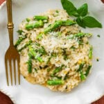 A plate of asparagus risotto with garnish and a fork.