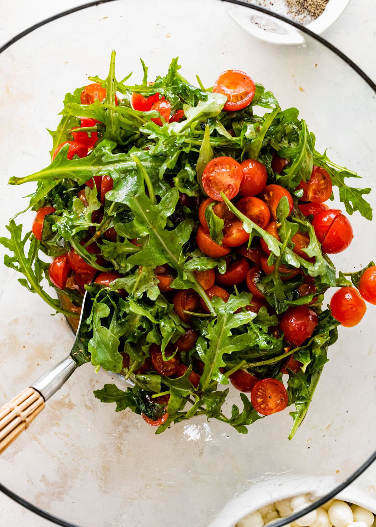 A bowl of salad with tomatoes and arugula.