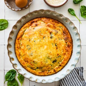 A baked Italian spinach frittata in a ceramic pie dish.