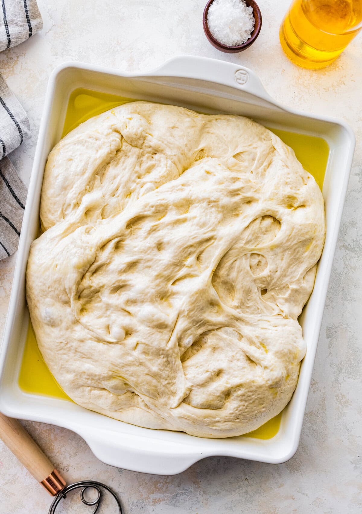 how to make no-knead focaccia bread step-by-step: Add the dough to a well oiled baking dish. Let it rise again.