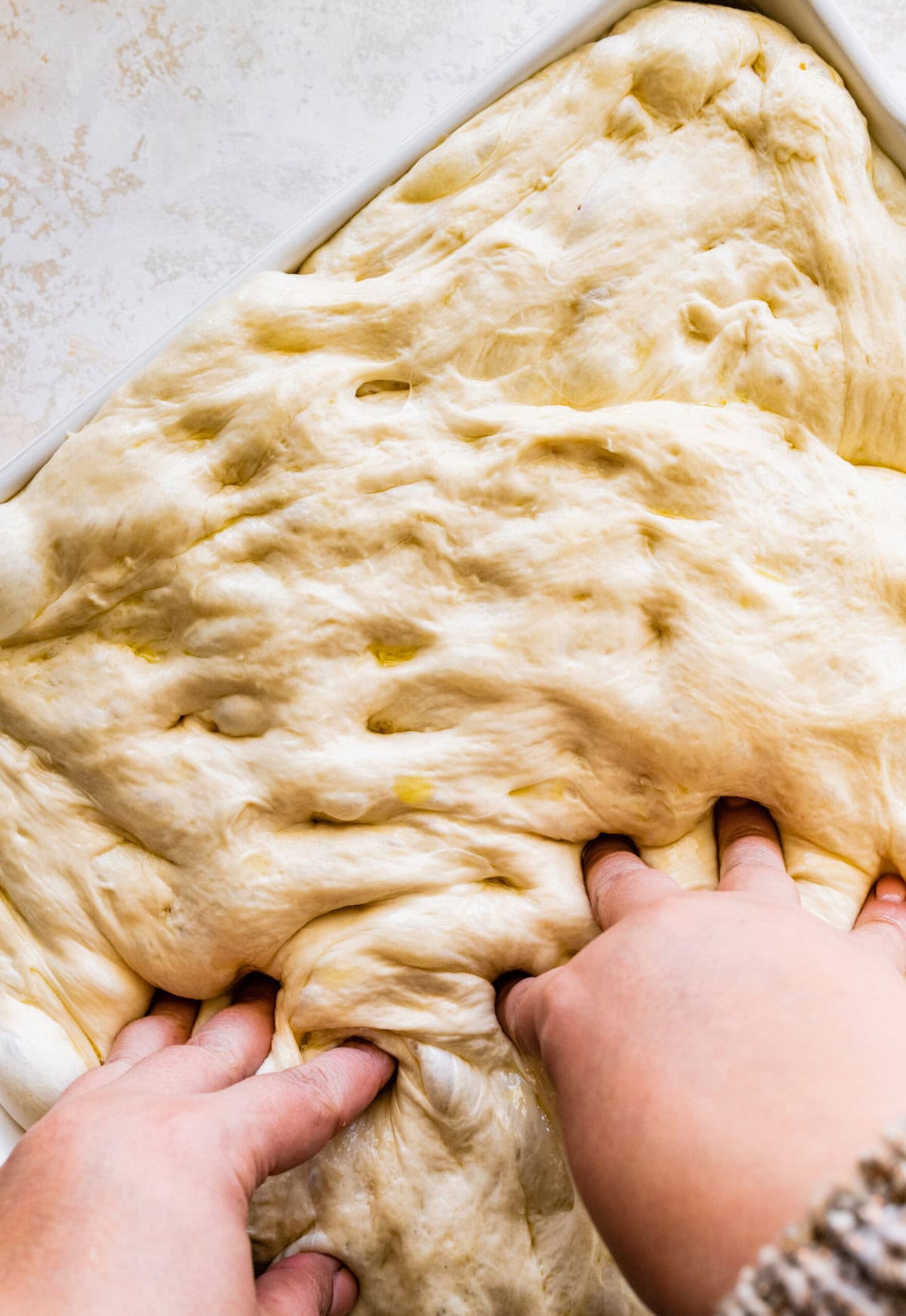 how to make no-knead focaccia bread step-by-step: with your hands make dimples with your fingers after the second rise.