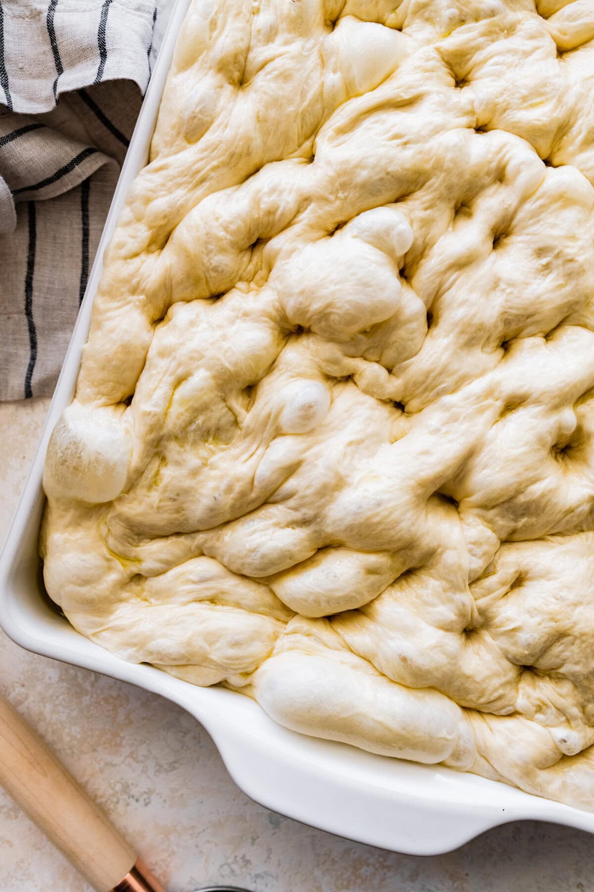 how to make no-knead focaccia bread step-by-step: dough with dimples. Ready to bake.