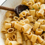 A pot of brown butter pasta with a wooden spoon in it.