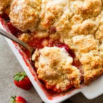 a baking dish of rhubarb cobbler with a spoon holding up some.