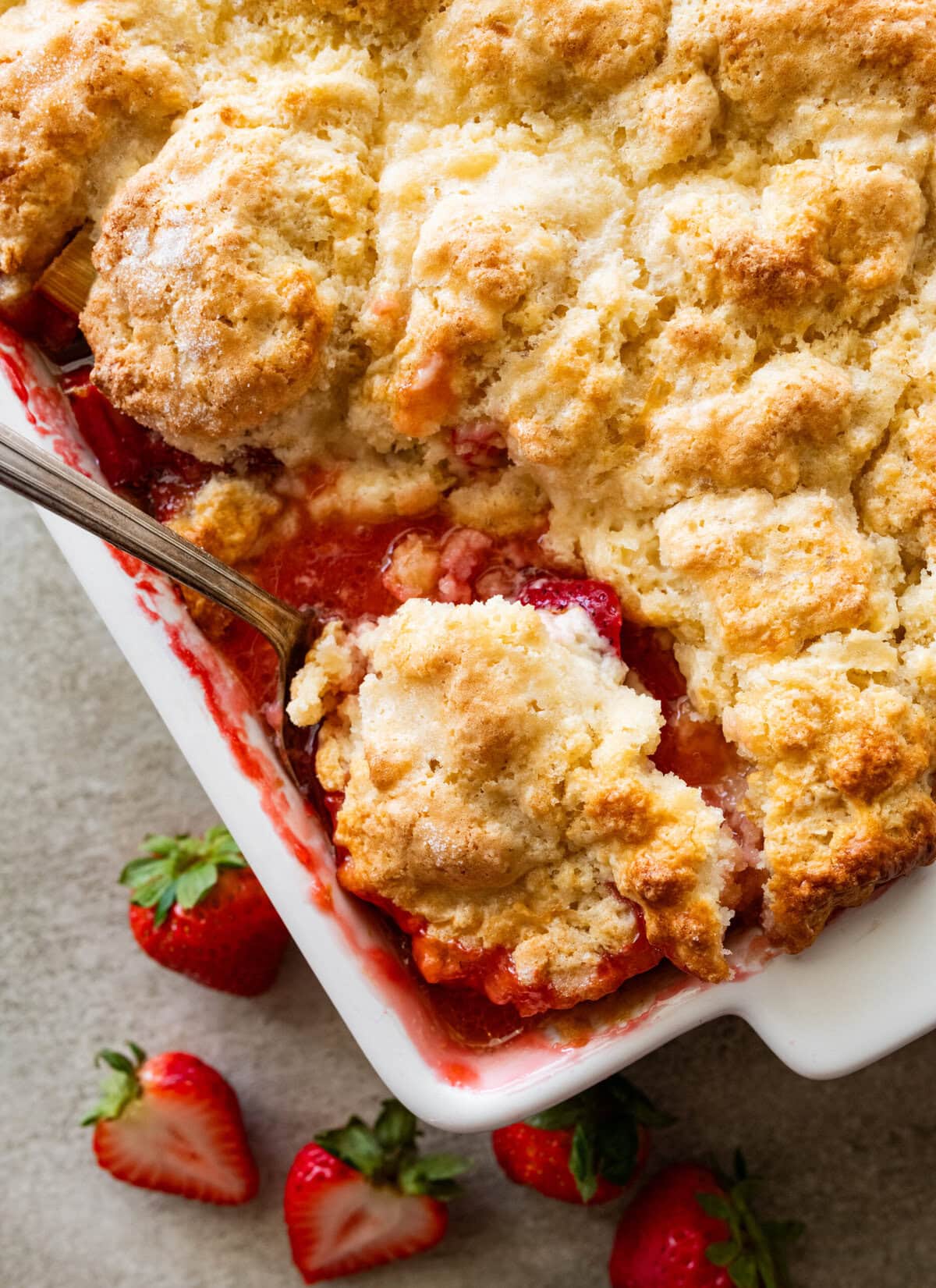 a baking dish of rhubarb cobbler with a spoon holding up some.