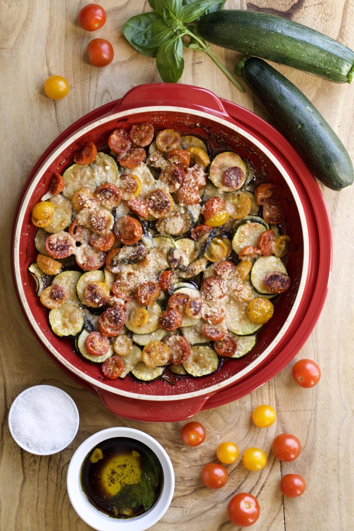 Red bowl of baked zucchini with bruschetta topping.