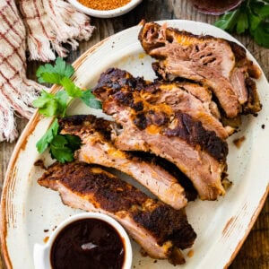 Juicy dry rub ribs on a plate. BBQ sauce on the side.