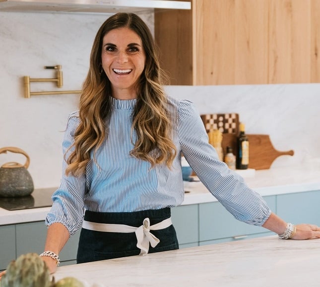 Elena in the kitchen wearing a blue dress shirt. Profile photo. 